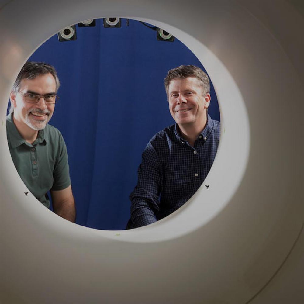 两名研究人员穿过开口，来到amjs澳金沙门开创的全身PET扫描机器前.